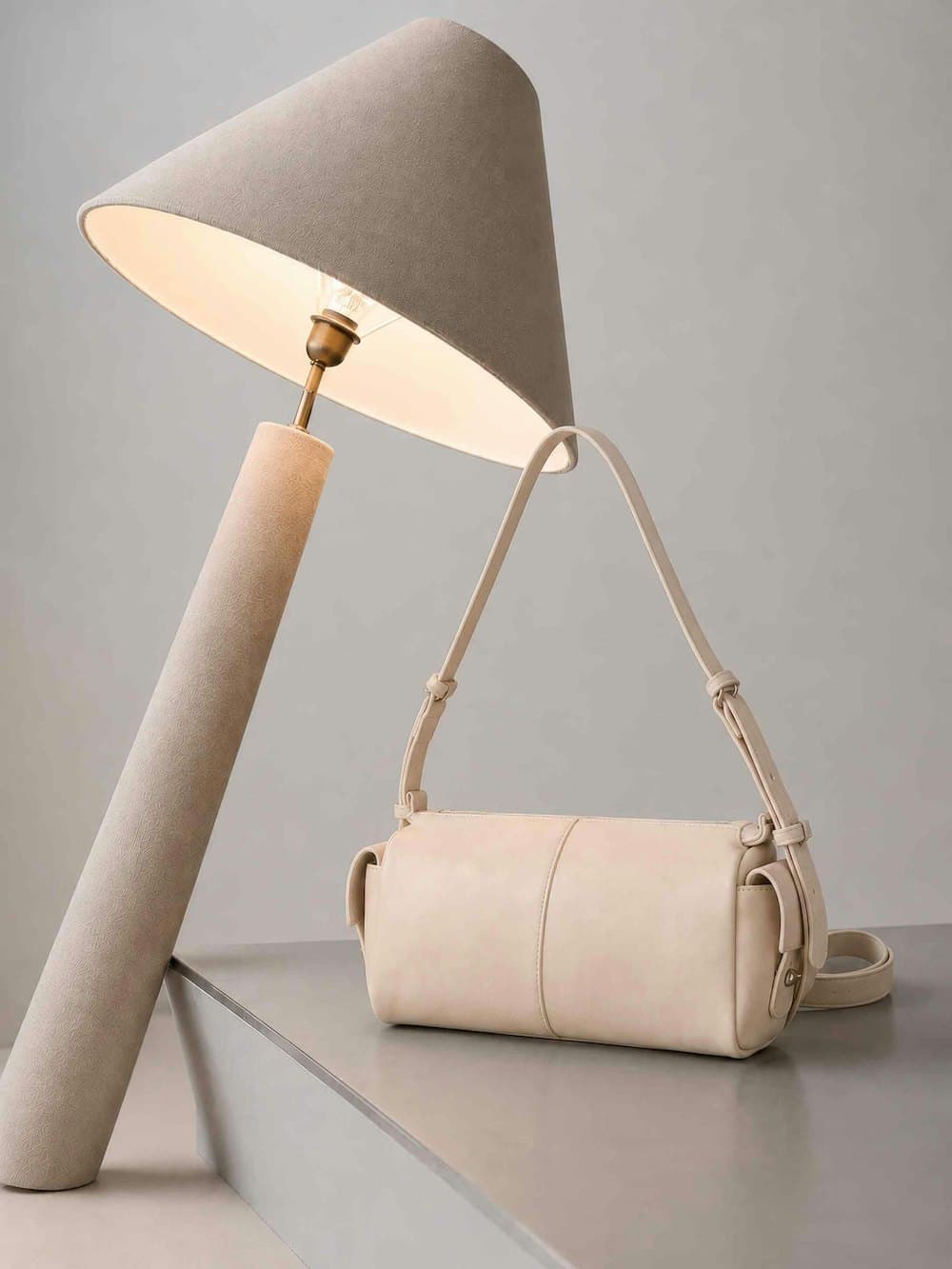 A cream leather shoulder bag photographed under studio light